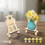 استند چوبی او خواهد آمد استند چوبی طرح «او خواهد آمد» با گلدان زرد و دسته‌ای گل نرگس، تزئینی معنادار و زیبا برای میز یا قفسه. مناسب هدیه مذهبی و یادبود انتظار.