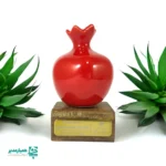 🍎 تندیس انار با پایه چوبی اختصاصی – نماد مهر و ماندگاری در شب یلدا شب یلدا در مدارس فرصتی ارزشمند است برای تقویت هویت فرهنگی، ایجاد خاطره‌ای دلنشین و قدردانی محترمانه از دانش‌آموزان، معلمان و همکاران 🎓✨ تندیس انار با پایه چوبی اختصاصی با الهام از نماد اصیل یلدا، تلفیقی از سادگی، زیبایی و مفهوم ماندگاری است 🍎 این تندیس بر روی پایه چوبی شکیل نصب شده و امکان درج نام مدرسه یا متن دلخواه روی پلاک آن وجود دارد. وزن مناسب (حدود ۴۰ گرم) و ابعاد استاندارد باعث می‌شود این تندیس گزینه‌ای ایده‌آل برای هدایای یلدایی مدارس با رویکرد رسمی و فرهنگی باشد 🎄 ابعاد: ۵ × ۴.۵ × ۹ سانتی‌متر 📐 وزن تقریبی: ۴۰ گرم ⚖️ دارای پایه چوبی اختصاصی و پلاک فلزی 🪵 قابلیت درج نام مدرسه یا متن سفارشی ✍️ مناسب هدیه شب یلدا در مدارس 🏫 این محصول از مجموعه هدایای فرهنگی همیار مدیر، انتخابی هوشمندانه برای مدیران و معاونان مدارس است که به هویت، نظم و ارزش‌گذاری فرهنگی توجه ویژه دارند ✅