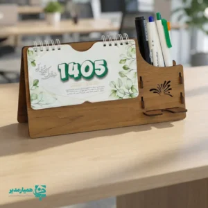 "📆 تقویم رومیزی کد 203 | انتخابی شیک برای میزهای حرفه‌ای تقویم رومیزی کد 203 با طراحی چوبی و ساختار جمع‌وجور، گزینه‌ای بسیار کاربردی برای میز کار در محیط‌های اداری، آموزشی و سازمانی است. این محصول با ظاهر گرم چوب و طراحی مینیمال، همزمان حس نظم، زیبایی و حرفه‌ای بودن را به میز شما می‌بخشد. بدنه این تقویم از MDF دورو با کیفیت بالا ساخته شده و ابعاد پایه آن 13*24 سانتی‌متر است که فضای کمی اشغال کرده و برای هر نوع میز کاری مناسب می‌باشد. برگه‌های تقویم با ابعاد 8.5*16 سانتی‌متر از کاغذ گلاسه 200 گرم تهیه شده‌اند که علاوه بر خوانایی بالا، از دوام و ماندگاری مناسبی برخوردار هستند. صحافی فنری، ورق‌زدن آسان و استفاده روزمره را بسیار راحت کرده است. ⭐ تقویم رومیزی کد 202 در رنگ‌3 رنگ متنوع (گردوجنگلی ،فندوقی،گردویی تیره ) تولید می‌شود تا با سلیقه‌ها و دکوراسیون‌های مختلف هماهنگ باشد. مهم‌ترین مزیت این محصول، قابلیت شخصی‌سازی اختصاصی آن است؛ امکان درج نام، لوگو یا اطلاعات سازمان، مدرسه یا برند این تقویم را به یک هدیه تبلیغاتی ماندگار و مؤثر تبدیل می‌کند. کد محصول: 202 جنس بدنه: MDF دورو ابعاد پایه13*24 سانتی‌متر ابعاد برگه:16*8.5سانتی‌متر کاغذ: گلاسه 200 گرم قابلیت شخصی‌سازی اختصاصی تقویم رومیزی کد 203؛ انتخابی هوشمندانه برای میز کار، هدیه سازمانی و تبلیغات ماندگار ✅ "
