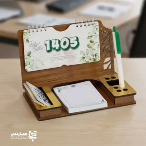 "📆 تقویم رومیزی کد 205 | انتخابی شیک برای میزهای حرفه‌ای تقویم رومیزی کد 205 با طراحی چوبی و ساختار جمع‌وجور، گزینه‌ای بسیار کاربردی برای میز کار در محیط‌های اداری، آموزشی و سازمانی است. این محصول با ظاهر گرم چوب و طراحی مینیمال، همزمان حس نظم، زیبایی و حرفه‌ای بودن را به میز شما می‌بخشد. بدنه این تقویم از MDF دورو با کیفیت بالا ساخته شده و ابعاد پایه آن 13*20 سانتی‌متر است که فضای کمی اشغال کرده و برای هر نوع میز کاری مناسب می‌باشد. برگه‌های تقویم با ابعاد 8.5*16 سانتی‌متر از کاغذ گلاسه 200 گرم تهیه شده‌اند که علاوه بر خوانایی بالا، از دوام و ماندگاری مناسبی برخوردار هستند. صحافی فنری، ورق‌زدن آسان و استفاده روزمره را بسیار راحت کرده است. ⭐ تقویم رومیزی کد 202 در رنگ‌3 رنگ متنوع (گردوجنگلی ،فندوقی،گردویی تیره ) تولید می‌شود تا با سلیقه‌ها و دکوراسیون‌های مختلف هماهنگ باشد. مهم‌ترین مزیت این محصول، قابلیت شخصی‌سازی اختصاصی آن است؛ امکان درج نام، لوگو یا اطلاعات سازمان، مدرسه یا برند این تقویم را به یک هدیه تبلیغاتی ماندگار و مؤثر تبدیل می‌کند. کد محصول: 205 جنس بدنه: MDF دورو ابعاد پایه13*20 سانتی‌متر ابعاد برگه:16*8.5سانتی‌متر کاغذ: گلاسه 200 گرم قابلیت شخصی‌سازی اختصاصی تقویم رومیزی کد 205؛ انتخابی هوشمندانه برای میز کار، هدیه سازمانی و تبلیغات ماندگار ✅ "
