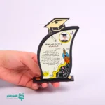 🏆 تندیس سفارشی «کلاه افتخار» | یادبود پیروزی در مسیر علم و دانش 🌟 تندیس کلاه افتخار محصولی منحصربه‌فرد از مجموعه‌ی کیمیا هنر است که با فرم شیک و مدرن کلاه فارغ‌التحصیلی طراحی شده است 🎩. این تندیس نه تنها برای جشن فارغ‌التحصیلی، بلکه برای گرامیداشت جشن الفبا، پایان دوره‌های آموزشی یا تقدیر از دانش‌آموزان ممتاز ایده‌آل می‌باشد 🥇. طراحی جذاب کناری تندیس، فضایی پر از شور و هیجان آموزشی را به تصویر می‌کشد؛ از موشک در حال پرتاب (نماد اوج‌گیری) گرفته تا مدادهای رنگی و نمادهای علمی 🌍. این محصول یک قاب اختصاصی برای درج عکس دانش‌آموز و درج متن تقدیرنامه سفارشی (شامل نام گیرنده و اهداکننده) دارد. 📝 📏 ابعاد: 14 × 8 × 2.5 سانتی‌متر (ارتفاع × عرض × عمق) ⚖️ وزن تقریبی: 33.5 گرم (سبک و قابل حمل) 🎨 جنس و رنگ: پایه چوبی تیره با برش لیزری و روکش مشکی/طلایی 🖼️ قابلیت شخصی‌سازی: جای عکس، درج متن دلخواه و امکان درج نام مجموعه (مثلاً همیار مدیر) 🎓 کاربرد: جوایز تحصیلی، یادبودهای آموزشی، هدایای جشن الفبا این تندیس به عنوان یک اثر هنری کاربردی، یادآور تلاش و موفقیت دانش‌آموزان است. با اعتماد به کیفیت ساخت کیمیا هنر و طراحی‌های هدفمند همیار مدیر، بهترین هدیه را برای قدردانی از زحمات آنان انتخاب کنید. 🚀 🎁 تندیس کلاه افتخار: هدیه‌ای که هرگز فراموش نمی‌شود! 📚