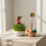 تاپر چوبی عمو نوروز | تزیین شاد و سنتی برای جشن‌های نوروزی 🌸🎂 تاپر چوبی طرح عمو نوروز یکی از اکسسوری‌های تزیینی و فرهنگی پرطرفدار ویژه ایام نوروز است که با الهام از شخصیت دوست‌داشتنی عمو نوروز و نمادهای هفت‌سین 🐟🍎🌿 طراحی شده است. لبخند گرم و رنگ‌های شاد این تاپر، حال‌وهوای بهار را به‌زیباترین شکل به جشن‌ها و مناسبت‌های نوروزی می‌بخشد. این محصول از چوب سبک و مرغوب تولید شده و با وزن تقریبی ۱۳ گرم، بسیار سبک، ایمن و مناسب استفاده در محیط‌های مختلف است. ابعاد ۱۶ × ۸ سانتی‌متر آن باعث شده به‌راحتی روی کیک، دسر، گلدان، میز پذیرایی یا سفره هفت‌سین قرار گیرد و جلوه‌ای چشم‌نواز ایجاد کند 🎂🌷 تاپر عمو نوروز 🌞🐣 گزینه‌ای عالی برای تزیین کیک نوروزی، جشن‌های مدارس و مهدکودک‌ها، پک‌های عیدانه فرهنگی و فعالیت‌های مناسبتی مجموعه همیار مدیر به‌شمار می‌رود. این محصول علاوه بر زیبایی ظاهری، پیام شادی، نو شدن و پاسداشت فرهنگ ایرانی را منتقل می‌کند 🌿✨ ویژگی‌های محصول: 🌸 طرح: عمو نوروز با استایل سنتی و شاد 🪵 جنس: چوب باکیفیت و سبک 📏 ابعاد: ۱۶ × ۸ سانتی‌متر ⚖️ وزن: حدود ۱۳ گرم 🎁 کاربرد: تزیین کیک، دسر، هفت‌سین و هدیه نوروزی همیار مدیر اگر به‌دنبال یک محصول زیبا، فرهنگی و متفاوت برای تزیین جشن‌های نوروزی 🍎🐟 هستید، تاپر چوبی عمو نوروز انتخابی هوشمندانه و ماندگار است که در کنار مجموعه‌های فرهنگی همیار مدیر جلوه‌ای خاص به نوروز شما می‌دهد 🌼🎉