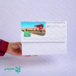 🗓️🇮🇷 تقویم‌های رومیزی ایران‌گردی «زمان به روایت» مجموعه‌ای فرهنگی و چشم‌نواز از کیمیا هنر است که در هر صفحه، شما را به گوشه‌ای از سرزمین تاریخ‌ساز ایران می‌برد. از بناهای باستانی و فرهنگی گرفته تا جاذبه‌های طبیعی و ملی، هر تصویر به زیبایی یادآور شکوه و تنوع سرزمین‌مان خواهد بود. ✨ این تقویم‌ها در سه اندازه بزرگ، متوسط و کوچک طراحی شده‌اند تا برای هر میز، سلیقه و فضای کاری گزینه‌ای مناسب و شکیل باشند. وزن بسیار سبک و ساختار مقاوم آن، استفاده‌ی روزمره را آسان و دل‌پذیر کرده است. 🎨 رنگ‌بندی خاص: مشکی، سفید و سبز — رنگ‌هایی الهام‌گرفته از هویت ایرانی و سادگی مینیمال. ترکیب این سه رنگ جلوه‌ای رسمی، فرهنگی و اصیل به فضای کاری شما می‌دهد. ✍️ قابلیت شخصی‌سازی: در بخش پایینی تقویم، می‌توانید نام شخصی یا عنوان مجموعه و سازمان خود را درج کنید. این ویژگی، آن را به انتخابی مناسب برای هدیه‌های فرهنگی، سازمانی و تبلیغاتی تبدیل کرده است. اگر به فرهنگ، تاریخ و زیبایی‌های این خاک علاقه‌مندید، تقویم رومیزی ایران‌گردی – تلفیقی از هویت ایرانی و طراحی مدرن است که حضورش بر روی میز کار شما حس غرور و آرامش وطن را زنده می‌کند. 🇮🇷🕰️ ✨ تولید و عرضه اختصاصی توسط کیمیا هنر