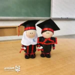 عروسک روسی فارغ‌التحصیلی – یادگاری شیرین روز موفقیت 🎓✨ عروسک روسی با لباس فارغ‌التحصیلی، یک هدیه جذاب و احساسی برای ثبت لحظه‌های شیرین فارغ‌التحصیلی است. طراحی این عروسک با استفاده از پارچه‌های باکیفیت و ترکیب رنگ مشکی و قرمز، حس رسمی بودن مراسم فارغ‌التحصیلی را در عین سادگی و لطافت عروسک‌های روسی منتقل می‌کند. این عروسک دوست‌داشتنی با ارتفاع حدود ۱۷ سانتی‌متر طراحی شده و اندازه‌ای بسیار مناسب برای قرار گرفتن روی میز مطالعه، شلف اتاق، ویترین و میز کار دارد. جزئیات لباس فارغ‌التحصیلی، کلاه، روبان‌ها و طومار کوچک در دست عروسک، همگی با دقت دوخته شده‌اند تا یک یادبود ماندگار از روز جشن باشد. عروسک روسی فارغ‌التحصیلی برای تمام مقاطع تحصیلی مناسب است؛ از پیش‌دبستانی و دبستان گرفته تا راهنمایی، دبیرستان و حتی مقاطع دانشگاهی. مدارس، آموزشگاه‌ها و خانواده‌ها می‌توانند از این عروسک به‌عنوان هدیه تقدیری در مراسم جشن فارغ‌التحصیلی استفاده کنند. اگر به‌دنبال یک هدیه خاص، متفاوت و احساسی برای دانش‌آموزان و دانشجویان هستید، این عروسک روسی با لباس فارغ‌التحصیلی می‌تواند یادگاری ماندگار از تلاش‌ها و موفقیت‌های آن‌ها باشد؛ هدیه‌ای که هر بار نگاه به آن، لبخند و خاطرات شیرین جشن را زنده می‌کند. 🌟