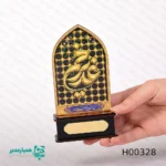 🕌 محراب غدیر خم؛ یادمانی هنری از عید ولایت به مناسبت بزرگداشت عید سعید غدیر خم، محراب غدیر از مجموعه آثار اختصاصی همیار مدیر معرفی می‌شود. این تندیس هنری با الهام از معماری اصیل اسلامی، تجسمی زیبا از پیوند هنر و معنویت است. این اثر با دقت بالا از ترکیب چوب و فلز ساخته شده و با وزن ایده‌آل ۳۰ گرم، گزینه‌ای بسیار مناسب برای هدیه در مراسم‌ها، هیئات و مدارس است. خط طلایی برجسته «غدیر» در دل یک قاب محرابی مشبک، جلوه‌ای چشم‌نواز به آن بخشیده است. یکی از ویژگی‌های متمایز این محصول، پلاک طلایی پایه آن است. این پلاک به شما اجازه می‌دهد نام، تاریخ یا پیام ویژه خود را بر روی آن حک کنید و این هدیه را به یادگاری اختصاصی و شخصی تبدیل نمایید. 💌 ویژگی‌های فنی محصول: طراحی اختصاصی برای جشن عید غدیر ساخته شده از چوب و فلز با کیفیت ابعاد محراب: ۱۱×۷ سانتی‌متر ابعاد پایه: ۷.۵×۳×۲.۵ سانتی‌متر وزن: ۳۰ گرم (سبک و قابل حمل) قابلیت درج متن یا نام سفارشی بر روی پلاک
