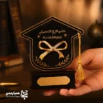 🎓 تندیس مینیاتوری پاپیون فارغ‌التحصیلی – نمادی از موفقیت و آغاز راه جدید 🎓 جلوه‌ای خاص و خاطره‌انگیز برای جشن‌های فارغ‌التحصیلی دانش‌آموزان با این تندیس زیبا و باکیفیت که توسط همیار مدیر طراحی شده است. این تندیس مینیاتوری از جنس چوب و فلز ساخته شده و با وزن سبک ۳۰ گرم، مناسب برای نگهداری و نمایش در میز یا کمد دانش‌آموزان است. ابعاد آن شامل پایه‌ای با اندازه‌های ۷.۵×۳×۲.۵ سانتی‌متر و کلاه فارغ‌التحصیلی به ابعاد ۱۰×۱۱ سانتی‌متر است که ترکیبی از ظرافت و قابلیتی ایده‌آل برای ساخت یک هدیه ماندگار ایجاد کرده است. این تندیس گزینه‌ای مناسب برای تمامی مقاطع تحصیلی بوده و برای هر دو گروه دختران و پسران می‌تواند یادگاری ارزشمندی باشد. شما می‌توانید نام، تاریخ یا متن دلخواه خود را روی آن درج کنید تا هدیه‌ای کاملاً شخصی و خاص بسازید. 🎁 با انتخاب این تندیس، علاوه بر تقدیر از تلاش‌های دانش‌آموزان، لحظات جشن فارغ‌التحصیلی را خاطره‌انگیزتر و ماندگارتر کنید و میز آن‌ها را با یک قطعه هنری زیبا و خاص تزئین نمایید.