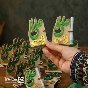 🕌✨ استند غدیر کد ۱ | هدیه‌ای شکیل، معنوی و بسیار خاص برای عید غدیر استند غدیر کد ۱ یکی از زیباترین محصولات همیار مدیر است که با ترکیب ام‌دی‌اف دورو، ام‌دی‌اف اکلیلی و مولتی‌استایل ساخته شده و جلوه‌ای بسیار دلنشین و مناسبتی دارد. طراحی آن کاملاً ویژه عید غدیر انجام شده و می‌تواند یک هدیه متفاوت و معنوی برای بزرگداشت این روز نورانی باشد. این استند در ارتفاع ۸.۵ سانتی‌متر و پایه‌ای به اندازه ۵.۸ سانتی‌متر تولید شده و به دلیل ابعاد مناسبش، هم برای قرار دادن روی میز و دکور عالی است و هم می‌توان آن را داخل پک‌های هدیه قرار داد. وجود جای مخصوص اسکناس روی بدنه استند، آن را برای عیدی دادن در عید غدیر بسیار کاربردی کرده است 💵✨. روی استند، نام زیبای حضرت علی (ع) با طرح اکلیلی چشم‌نواز دیده می‌شود و در بخش پایین، عبارت معنوی و محبوب «مولا کنت» حک شده است که جلوه‌ای روحانی و محترمانه به محصول می‌بخشد. 📌 ویژگی‌های محصول 📏 ارتفاع: ۸.۵ سانتی‌متر 📐 پایه: ۵.۸ سانتی‌متر 🪵 جنس: ام‌دی‌اف دورو + ام‌دی‌اف اکلیلی + مولتی‌استایل 💵 دارای قسمت مخصوص قرار دادن اسکناس عیدی 🕌 طراحی ویژه عید غدیر با جلوه‌ای بسیار زیبا و شیک 🎁 مناسب برای پک‌های هدیه، مدارس، مساجد و مراسم عید غدیر اگر به دنبال هدیه‌ای معنوی، خاص و در عین حال کاربردی برای عید غدیر هستید، این استند زیبا می‌تواند انتخابی فوق‌العاده باشد و لحظات این عید بزرگ را ماندگارتر کند ✨🌿.