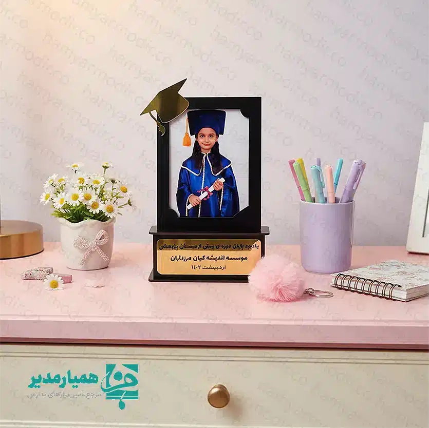 🎓🌟 تندیس فارغ‌التحصیلی قاب عکس – یادگاری باشکوه از لحظه‌های موفقیت تحصیلی ✨📚 تندیس فارغ‌التحصیلی قاب عکس، هدیه‌ای خاص و ماندگار برای ثبت خاطرات شیرین پایان سال تحصیلی است 💛🎉. طراحی این محصول بدون چاپ عکس انجام شده تا امکان قرار دادن تصویر دانش‌آموز در ابعاد 📸 ۱۰×۱۵ سانتی‌متر فراهم باشد. وجود عنصر نمادین 🎓 کلاه فارغ‌التحصیلی در بالای قاب، حس افتخار و موفقیت تحصیلی را زیبایی خاصی می‌بخشد 🌈👏. جنس این تندیس از چوب باکیفیت 🪵 بوده و با وزن سبک حدود ⚖️ ۵۵ گرم، انتخابی ایده‌آل برای قرار دادن روی میز، شلف یا ویترین محسوب می‌شود 💫. تلفیق شیک طراحی کلاسیک با جزئیات لطیف کودکانه، آن را به گزینه‌ای مناسب برای فضای آموزشی و فرهنگی تبدیل کرده است 🏫💖. این تندیس پیشنهاد ویژه‌ای برای 🎈 جشن الفبا و 🎉 فارغ‌التحصیلی مقاطع پیش‌دبستان و ابتدایی است تا خاطرات نخستین موفقیت‌های تحصیلی کودکان را جاودانه سازد 🧸🌟. محصولی زیبا، کاربردی و پرطرفدار برای مدارس، آموزشگاه‌ها و مراکز فرهنگی جهت تقدیر از تلاش‌های کوچک ولی پرافتخار کودکان 💐🎁.
