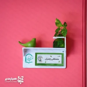  تابلو ی چوبی سر در حس خوب ؛ ترکیب زیبایی و نظم در فضای اداری تابلو چوبی سر در حس خوب راهکاری حرفه‌ای برای نظم‌دهی و زیباسازی فضاهای اداری و آموزشی است. این تابلو با طراحی مدرن  علاوه بر معرفی اتاق‌ها، جلوه‌ای شیک و منظم به محیط کار شما می‌بخشد. استفاده از متریال  پلکسی گلاس در ساخت این محصول باعث شده تا در برابر گردوغبار، رطوبت و ضربه مقاومت بالایی داشته باشد. بنابراین این تابلو گزینه‌ای مناسب برای نصب در مدارس، شرکت‌ها، سازمان‌ها و موسسات آموزشی محسوب می‌شود. ویژگی‌های اصلی محصول ساخته شده از پلکسی گلاس باکیفیت طراحی مدرن و جذاب مناسب محیط‌های اداری و آموزشی مقاوم در برابر گردوغبار و ضربه نصب آسان روی دیوار یا درب اتاق مناسب برای معرفی اتاق مدیریت، کلاس‌ها و بخش‌های مختلف سازمان همراه با گلدان(بدون گل) و پرنده سفالی امکان سفارشی‌سازی یکی از مهم‌ترین مزایای این محصول، امکان طراحی اختصاصی است. شما می‌توانید نام اتاق، لوگوی مجموعه یا هر متن دلخواه را روی تابلو درج کنید تا هویت بصری سازمان شما به شکلی حرفه‌ای نمایش داده شود. این تابلو گزینه‌ای ایده‌آل برای مدارس، شرکت‌ها، دفاتر اداری و موسسات آموزشی است و به مراجعه‌کنندگان کمک می‌کند مسیر خود را سریع‌تر پیدا کنند، در حالی که ظاهر محیط نیز مرتب و حرفه‌ای باقی می‌ماند.
